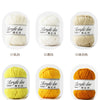 Six balls of soft acrylic yarn in various colors including white, yellow, and orange for knitting and crochet