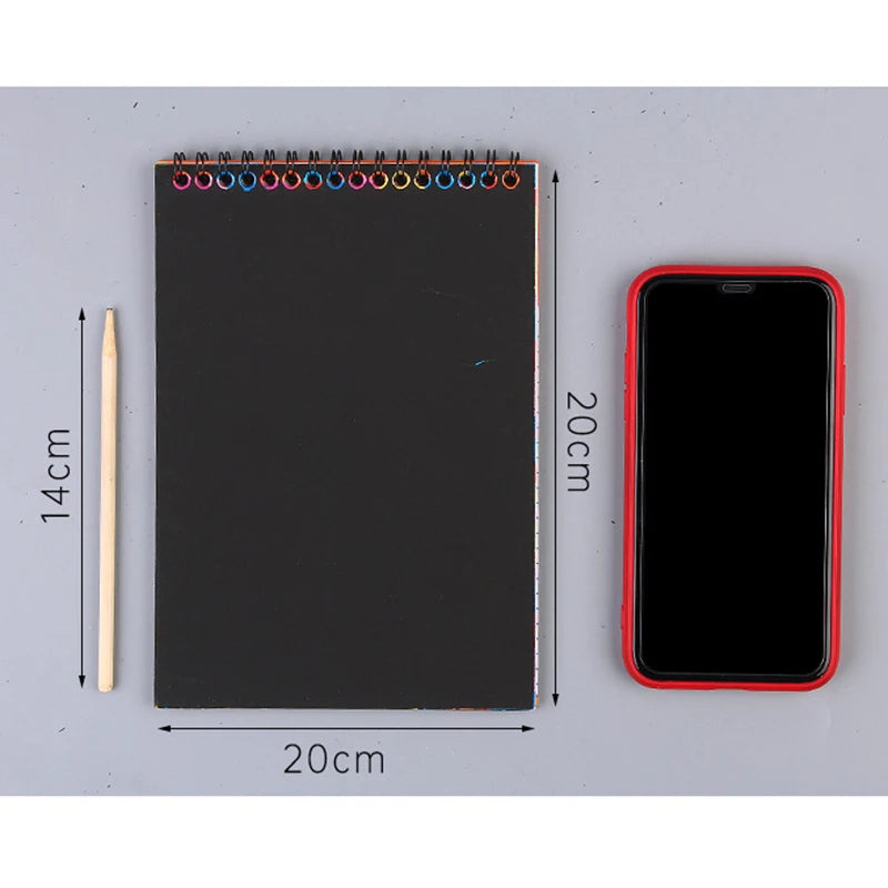 A black notebook with a rainbow scratch art paper set and a smartphone displayed next to it.