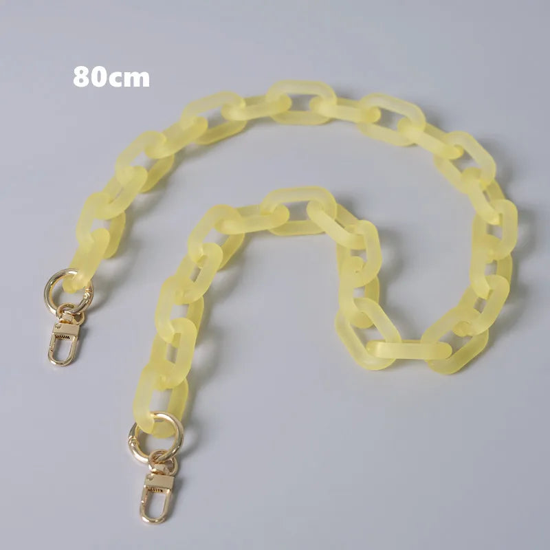 Geliges abnehmbares Kettchenriemen-Accessoire für eine Damenhandtasche, auf einer grauen Oberfläche ausgebreitet.