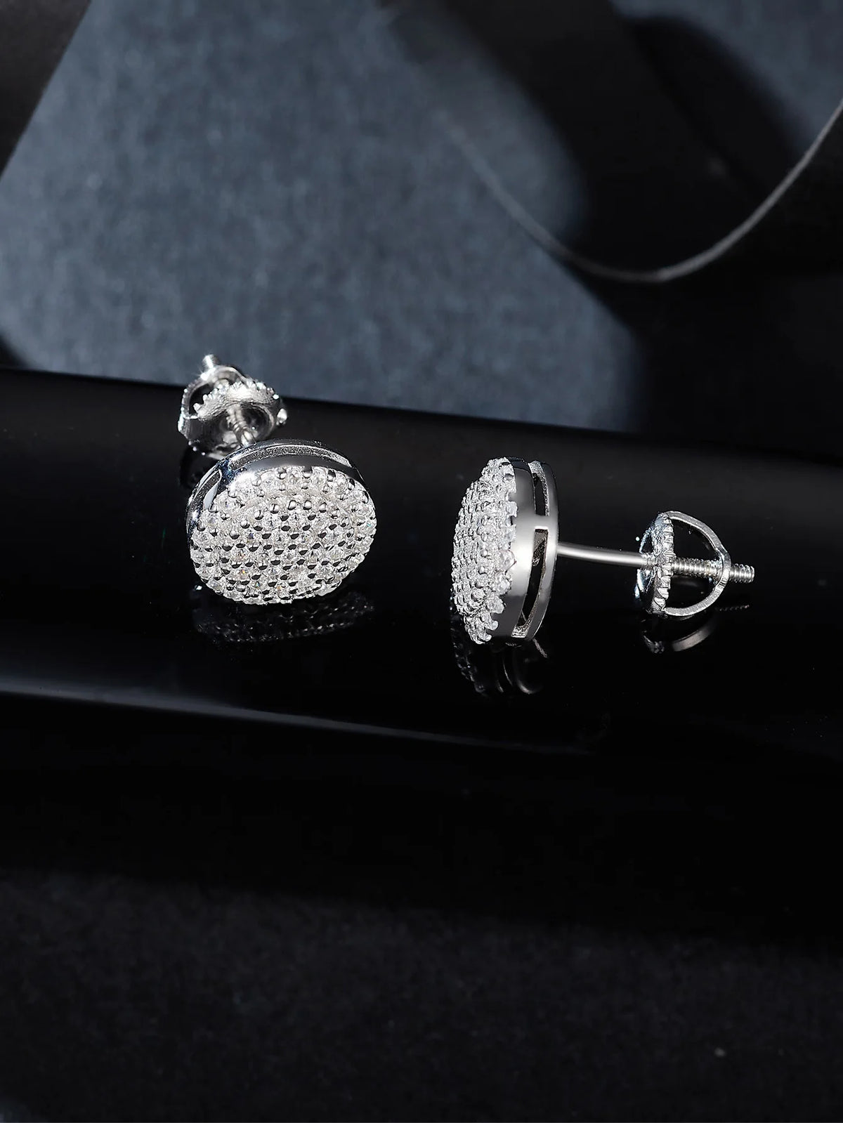 Boucles d'oreilles à diamants moissanite ronds en argent sterling sur une surface sombre.