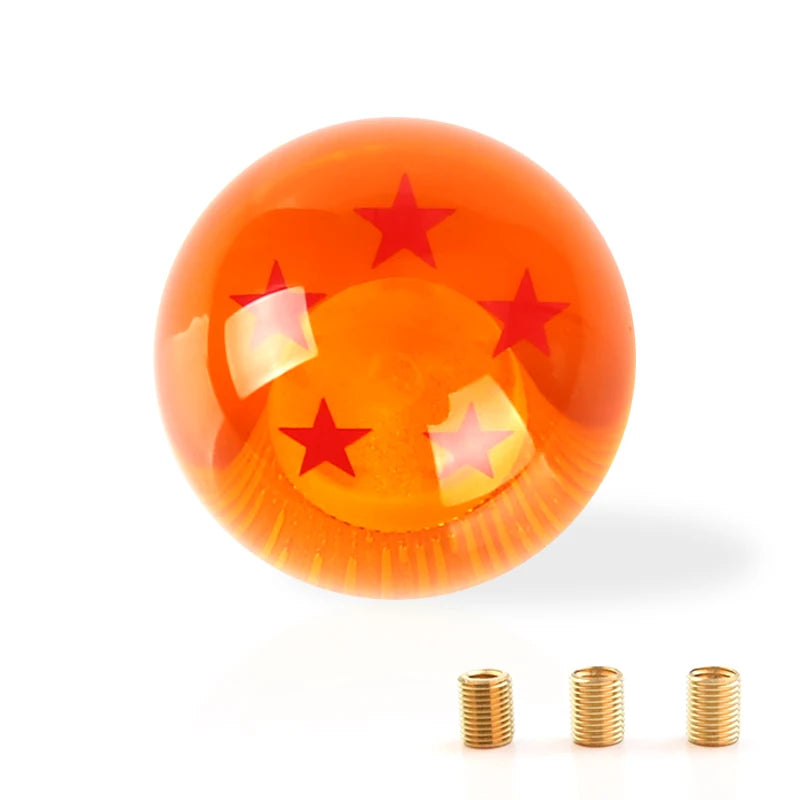 A glossy orange shift knob with a star design and several small brass rings shown against a white background.