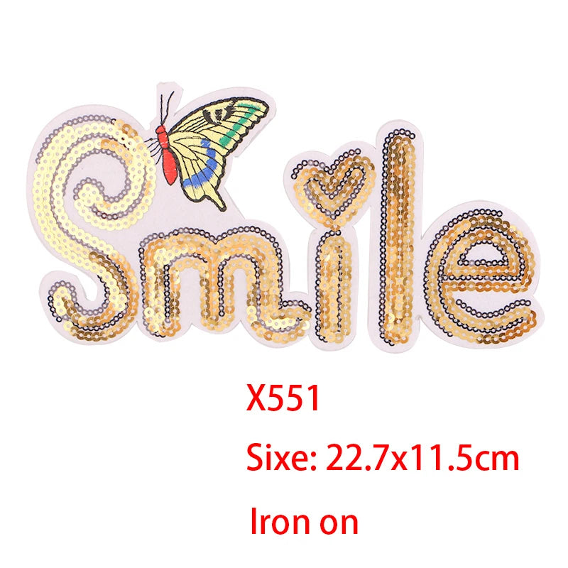 Iron-on patch featuring a smiling face made of gold and pink sequins with a butterfly detail