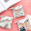A collection of cosmetic storage pouches in various floral and neutral patterns, including a light beige pouch and a pink pat