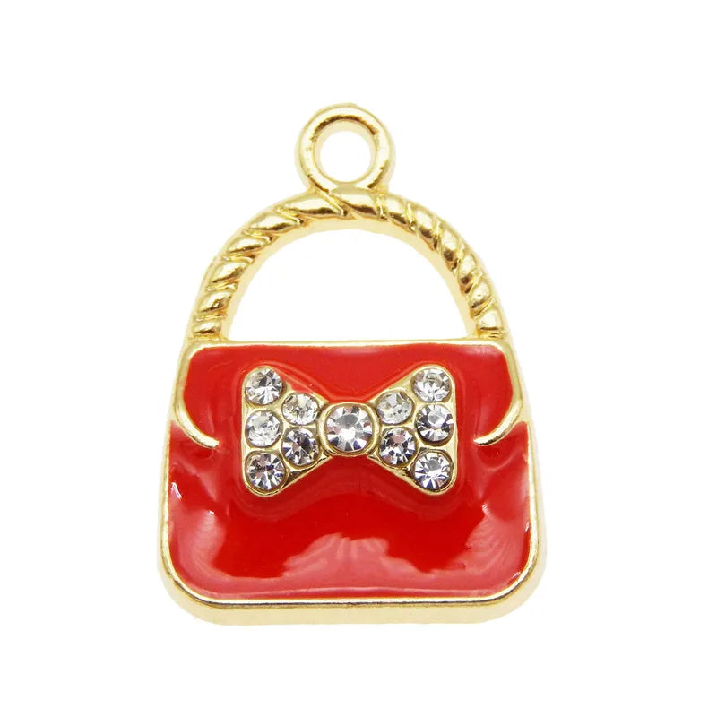 A set of six gold-toned handbag charm pendants featuring red enamel and clear crystal accents.