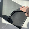 A hand is opening a gray iPad case, revealing a black mesh pencil holder inside.