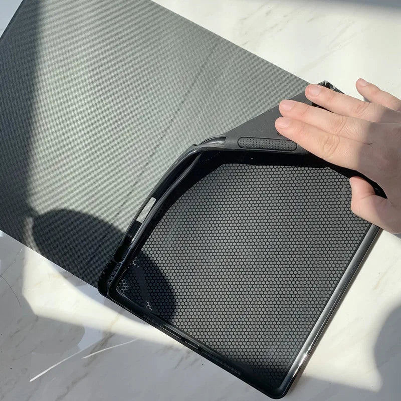 A hand is opening a gray iPad case, revealing a black mesh pencil holder inside.