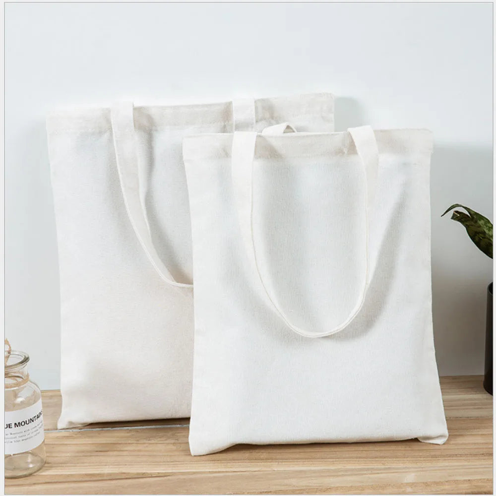 A white canvas tote bag is shown standing on a wooden surface.