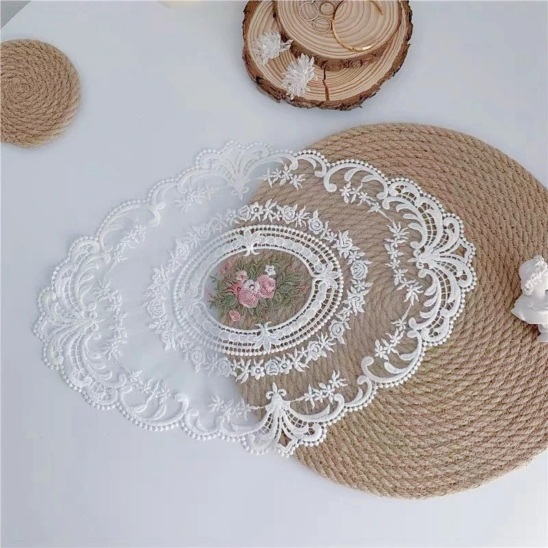 A round woven placemat with an oval white lace embroidery and a wooden slice nearby.