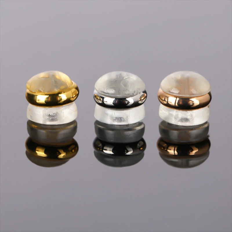Three silicone rubber ear back stoppers with copper rings shown on a reflective surface.