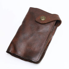A brown vintage cowhide leather bi-fold wallet with a brass logo detail.