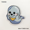 A light blue and gray embroidered patch of a smiling, blob-like creature with pink accents.
