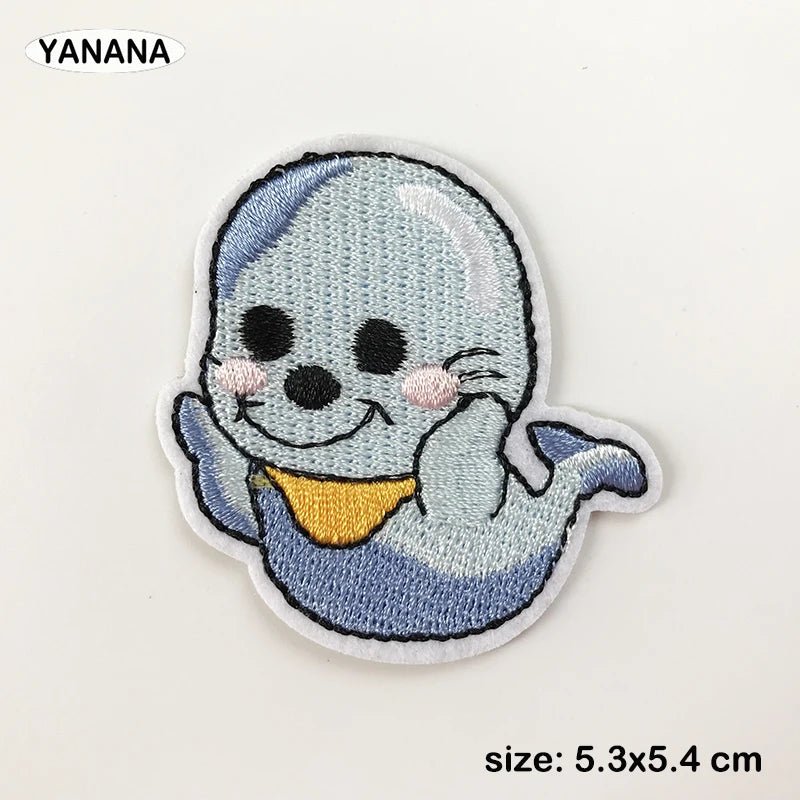A light blue and gray embroidered patch of a smiling, blob-like creature with pink accents.