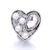 A heart-shaped silver metal snap button featuring clear and white pearls and rhinestones for jewelry making.