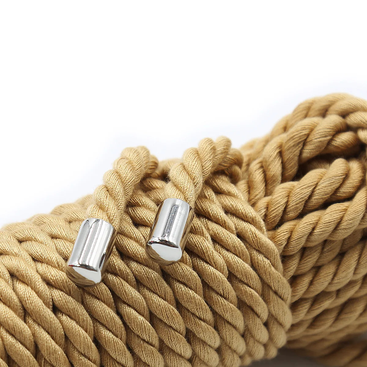 A close-up of thick, tan braided rope with silver metal tips used for Shibari bondage.