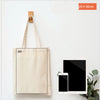A beige canvas tote bag with an A4 size, displayed next to a tablet and a smartphone.