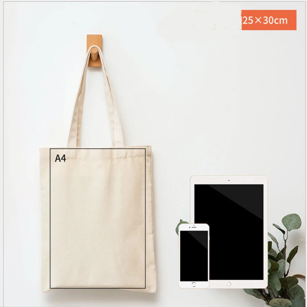 A beige canvas tote bag with an A4 size, displayed next to a tablet and a smartphone.