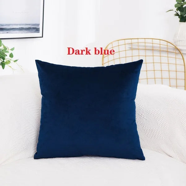 A dark blue velvet decorative cushion cover resting on a white sofa.