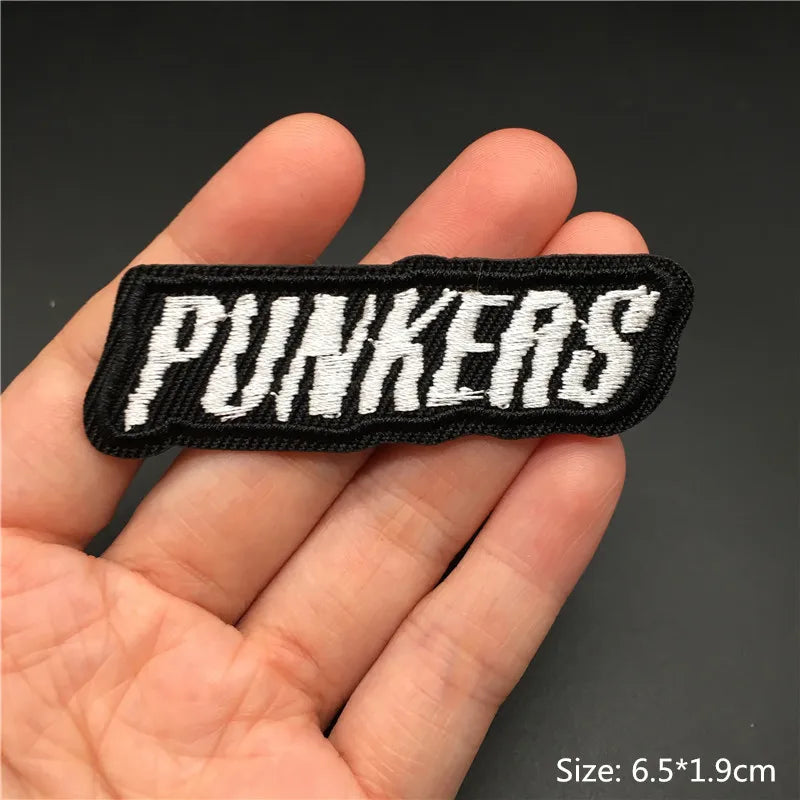 Black embroidered text PUNKERS on a fabric patch being held in a hand.