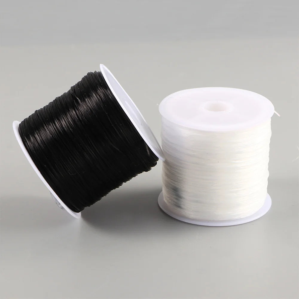A spool of black elastic crystal beading cord for jewelry making is shown next to a white spool.