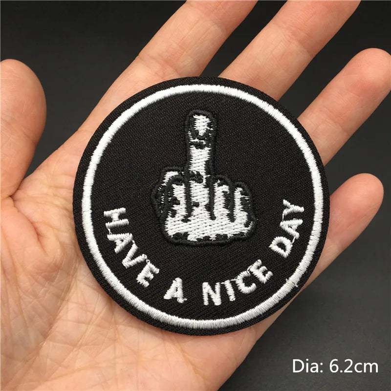 Black embroidered patch with a white hand gesture and the text HAVE A NICE DAY on a hand.