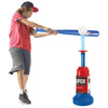 A child is using a blue pitching machine set with a bat and balls for practice.