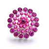 A cluster of pink and magenta round metal snap buttons used for jewelry making.