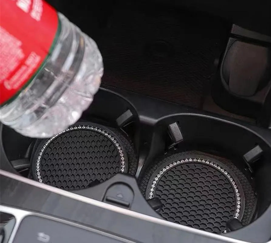 A clear glass bottle is shown next to a black non-slip cup mat designed for car interiors.