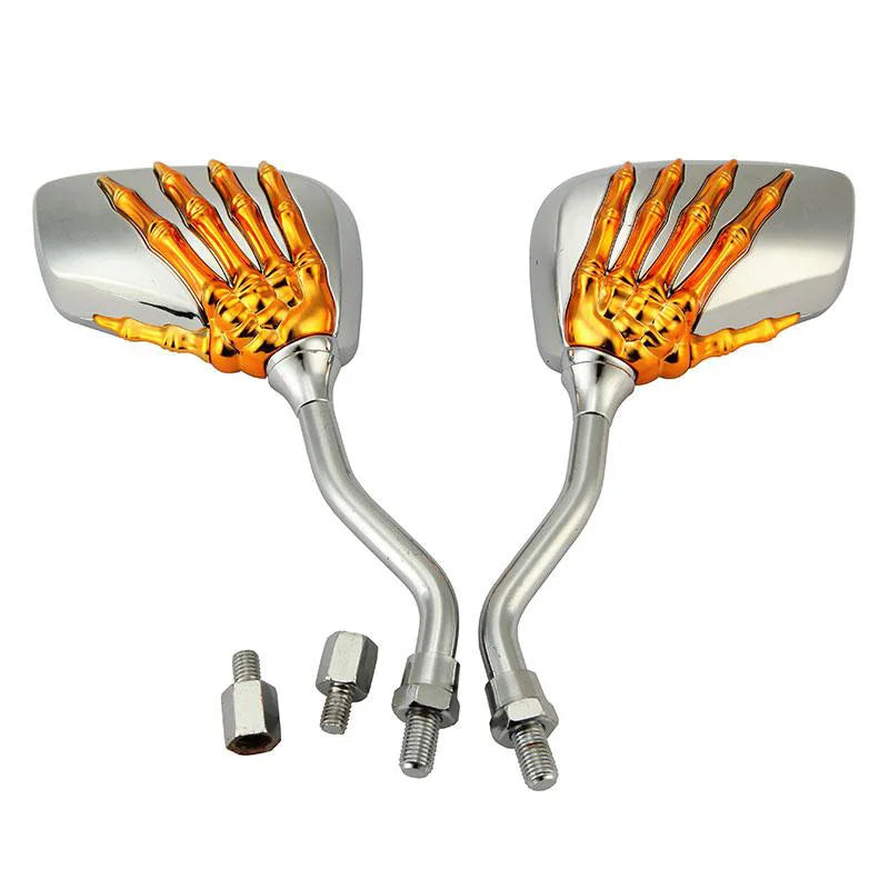 A set of two universal skull hand motorcycle side mirrors with gold-colored grips and silver housings.
