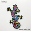 An embroidered patch of a colorful lizard or gecko with bright yellow and blue accents.
