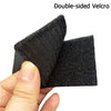 A hand holds a double-sided Velcro patch with black fabric and reflective accents.