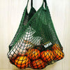 A green mesh produce bag filled with oranges and other fruits.