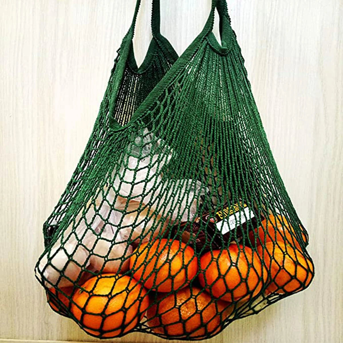 A green mesh produce bag filled with oranges and other fruits.