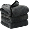 A stack of dark gray microfiber car drying towels with black trim.