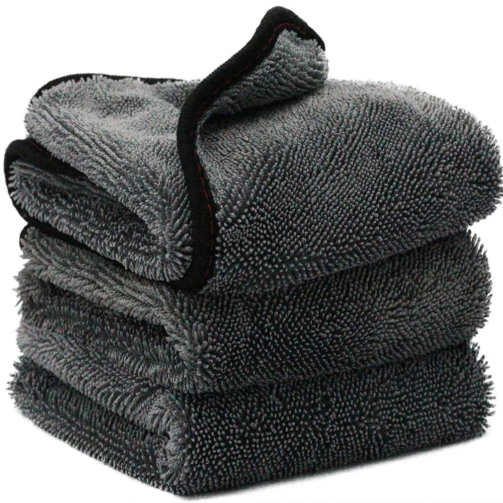A stack of dark gray microfiber car drying towels with black trim.