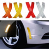 Two packs of reflective safety stickers shaped like Xs in orange and yellow colors applied to a car fender.