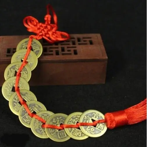 A necklace made of gold coins tied with a red handmade knot, displayed next to a wooden box.