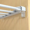 A white adhesive shelf support peg holder with multiple rods mounted on a wooden surface.