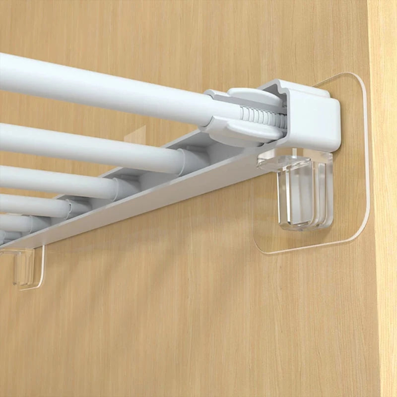 A white adhesive shelf support peg holder with multiple rods mounted on a wooden surface.