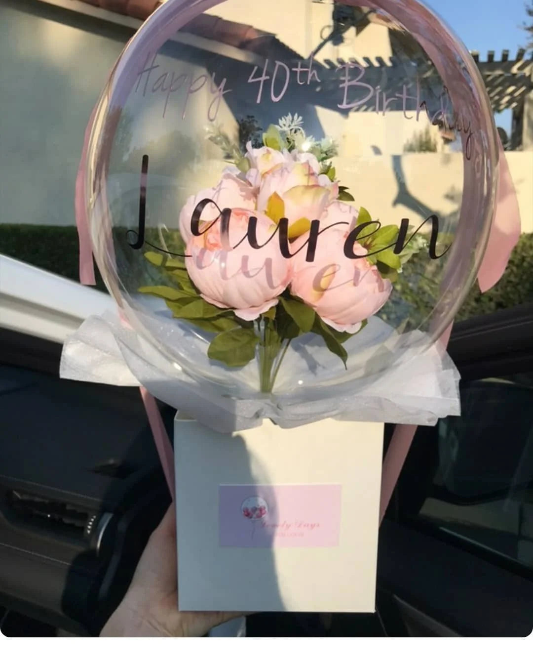 A clear balloon filled with pink flowers and text wishing a happy 40th birthday.