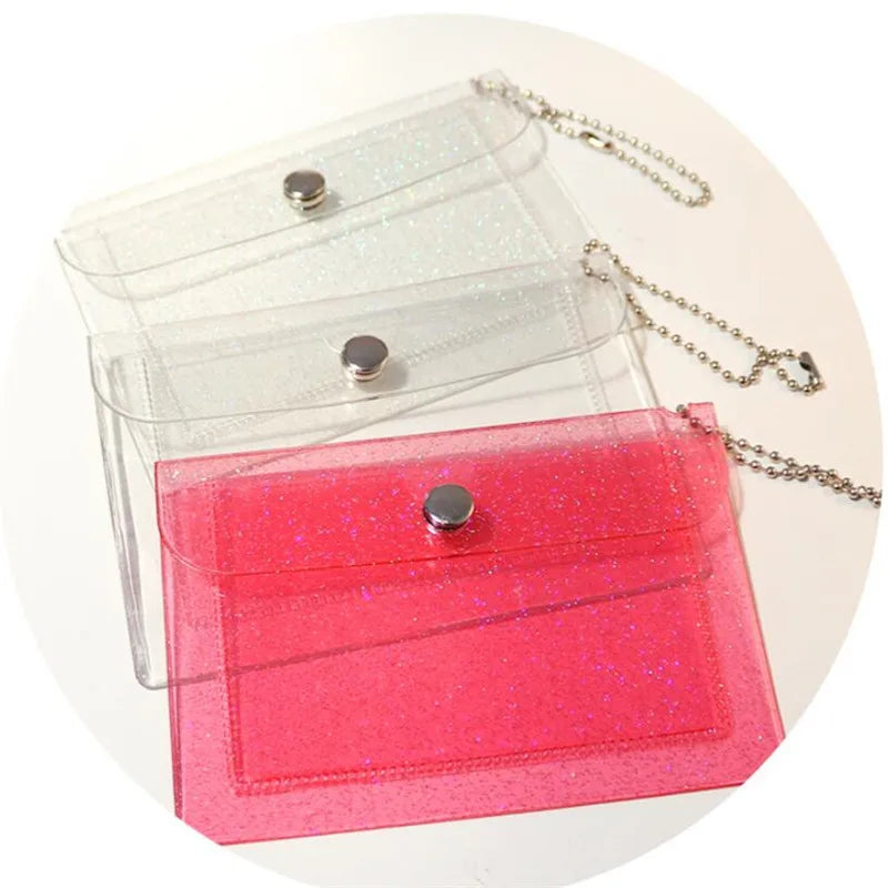 A set of three glitter PVC card holders in clear, pink, and magenta colors with gold chains.