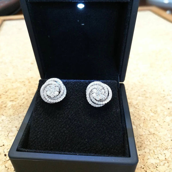 A pair of silver-toned geometric cubic zirconia stud earrings displayed in a black velvet jewelry box.