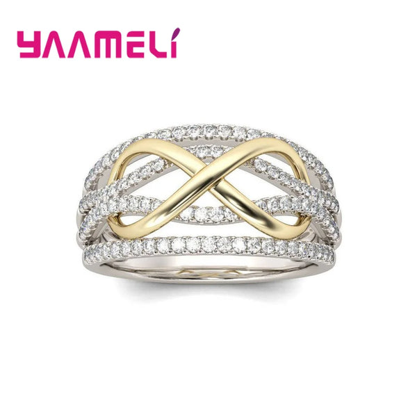 A silver ring featuring an infinity design with a gold bowknot and surrounding cubic zirconia stones.