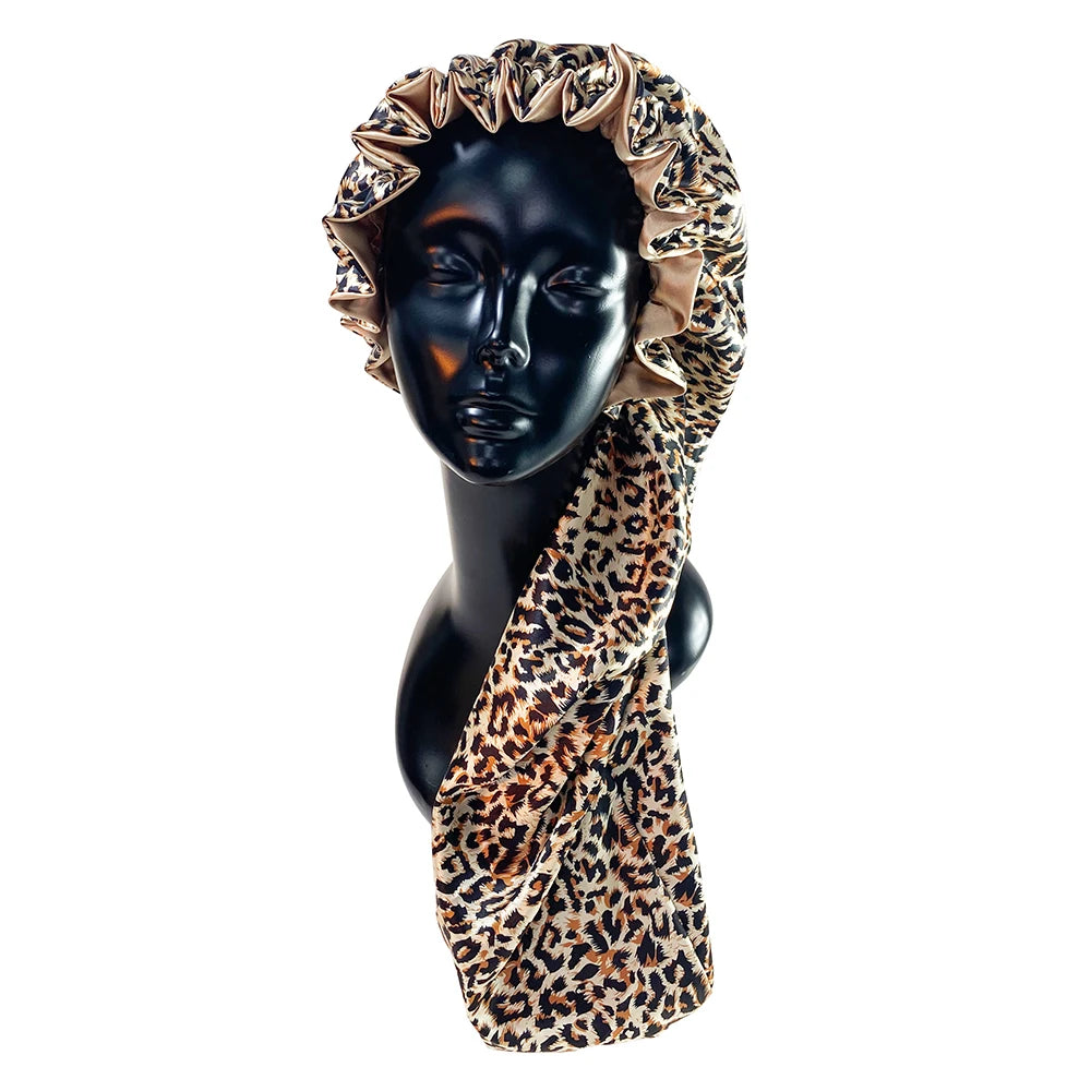 A black mannequin head wearing a leopard print satin hair bonnet with ruffled edges.