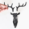 A black vintage deer head wall hook featuring antlers, displayed next to a sculpted deer head.