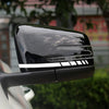 A close-up of a black reflective vinyl mirror decal installed on a vehicle, showing horizontal light strips.