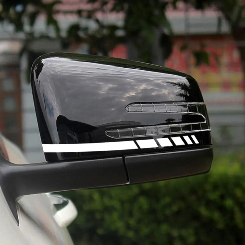 A close-up of a black reflective vinyl mirror decal installed on a vehicle, showing horizontal light strips.