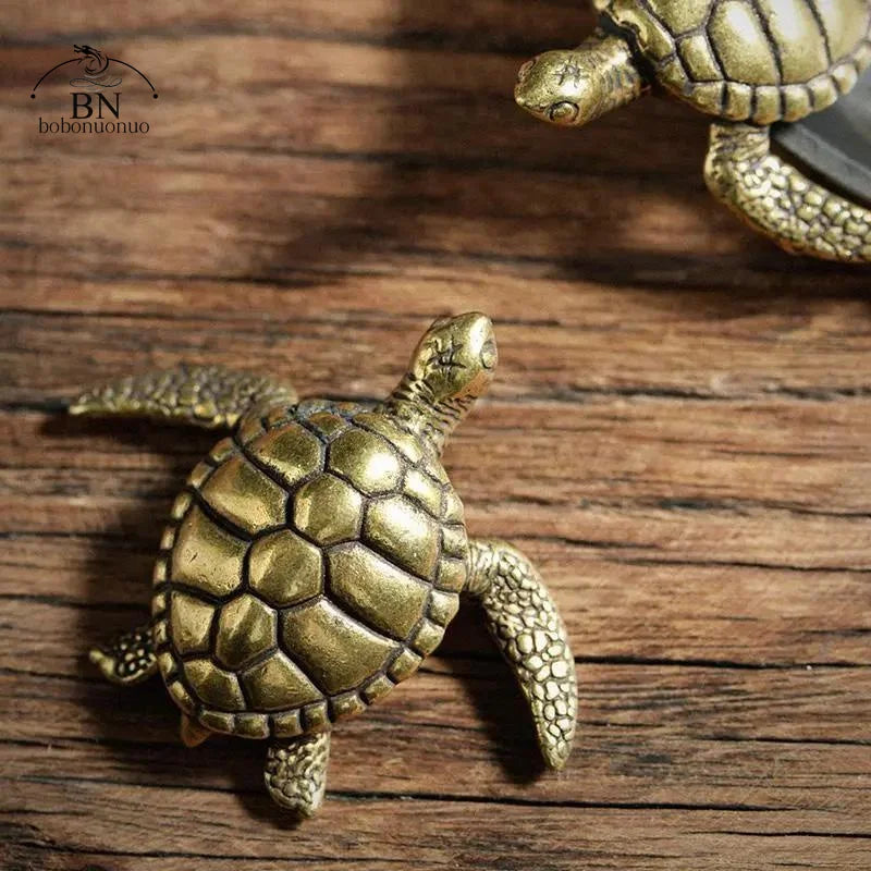 A detailed antique gold copper turtle figurine resting on a wooden surface.