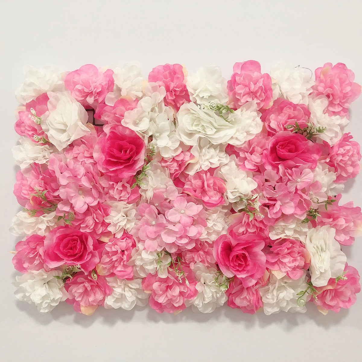 A dense wall panel of pink and white silk rose flowers for weddings and events.