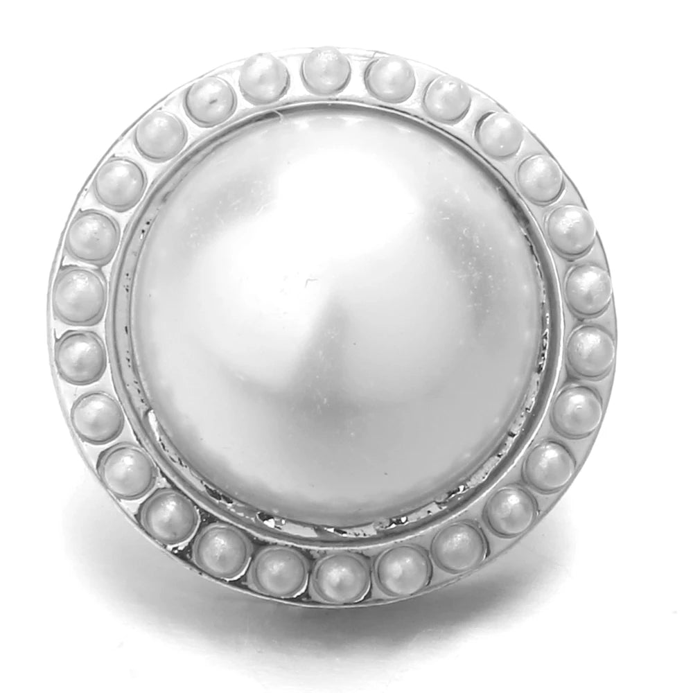 A round, silver-toned metal snap button with a textured, beaded rim and a smooth, reflective center.