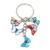 A colorful butterfly keychain charm with pink, teal, and red wings attached to a silver ring.